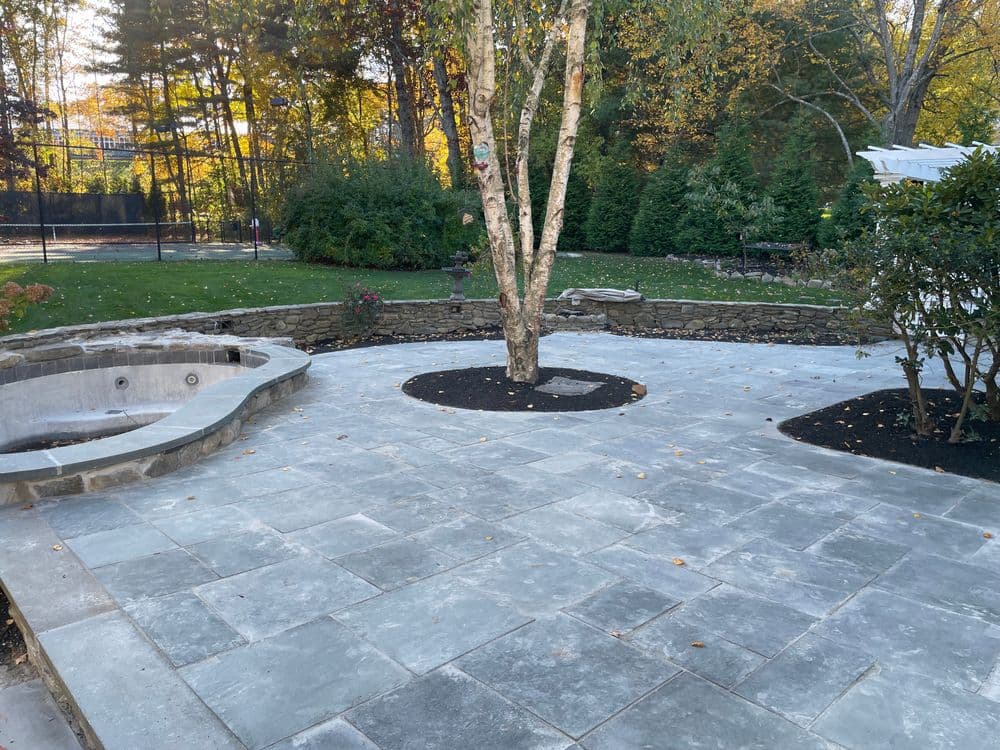 Modern patio with stone pavers, surrounded by landscaping and a relaxing spa area.