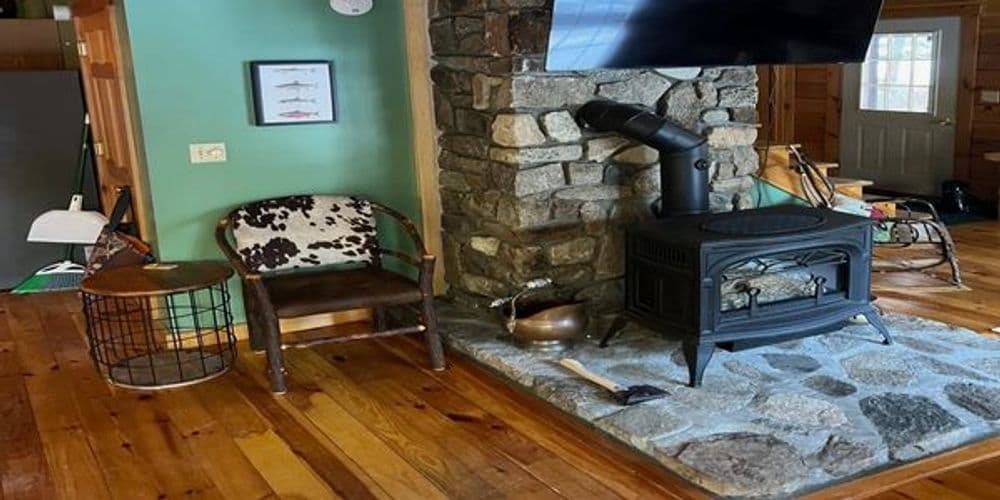 Cozy living room with stone fireplace, wood stove, and rustic seating.